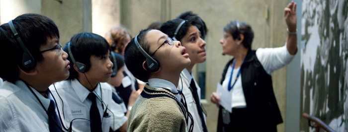 students on a field trip in a museum listening