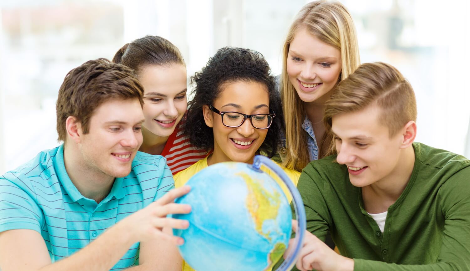 five smiling students looking at earth globe
