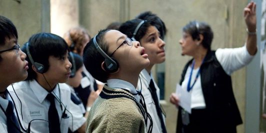 students on a field trip in a museum listening