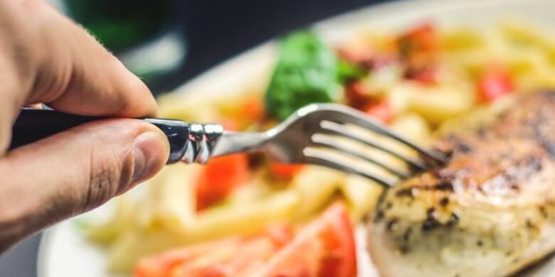 hand holding fork and picking food on a nice plate