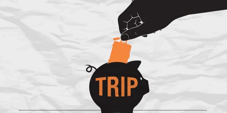 image showing a hand putting a little suitcase in a piggy bank